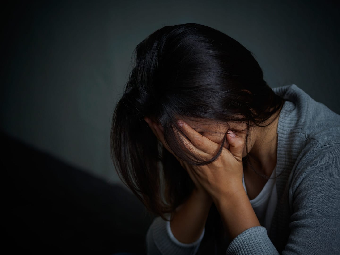 sad woman hug her knee and cry. Sad woman sitting alone in a empty room.