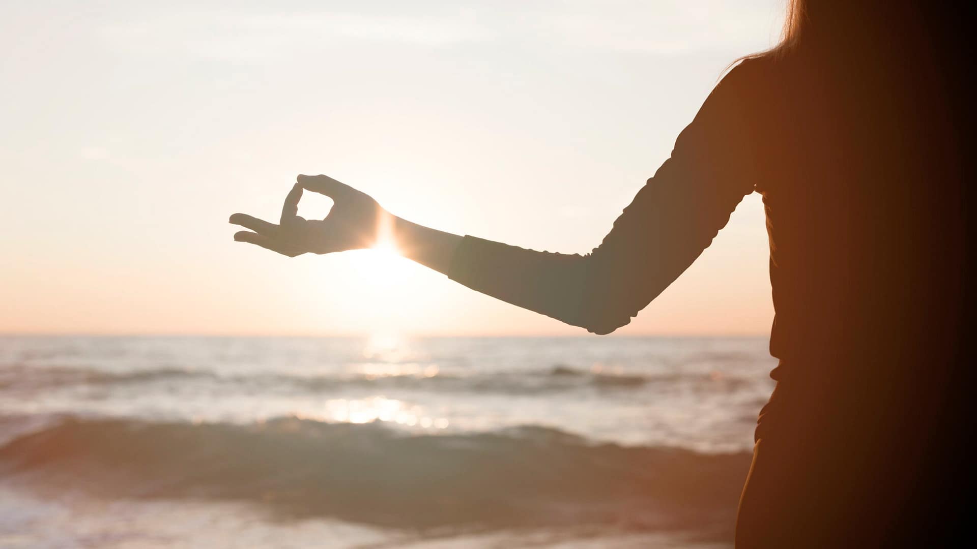 woman-meditating-sunset-beach