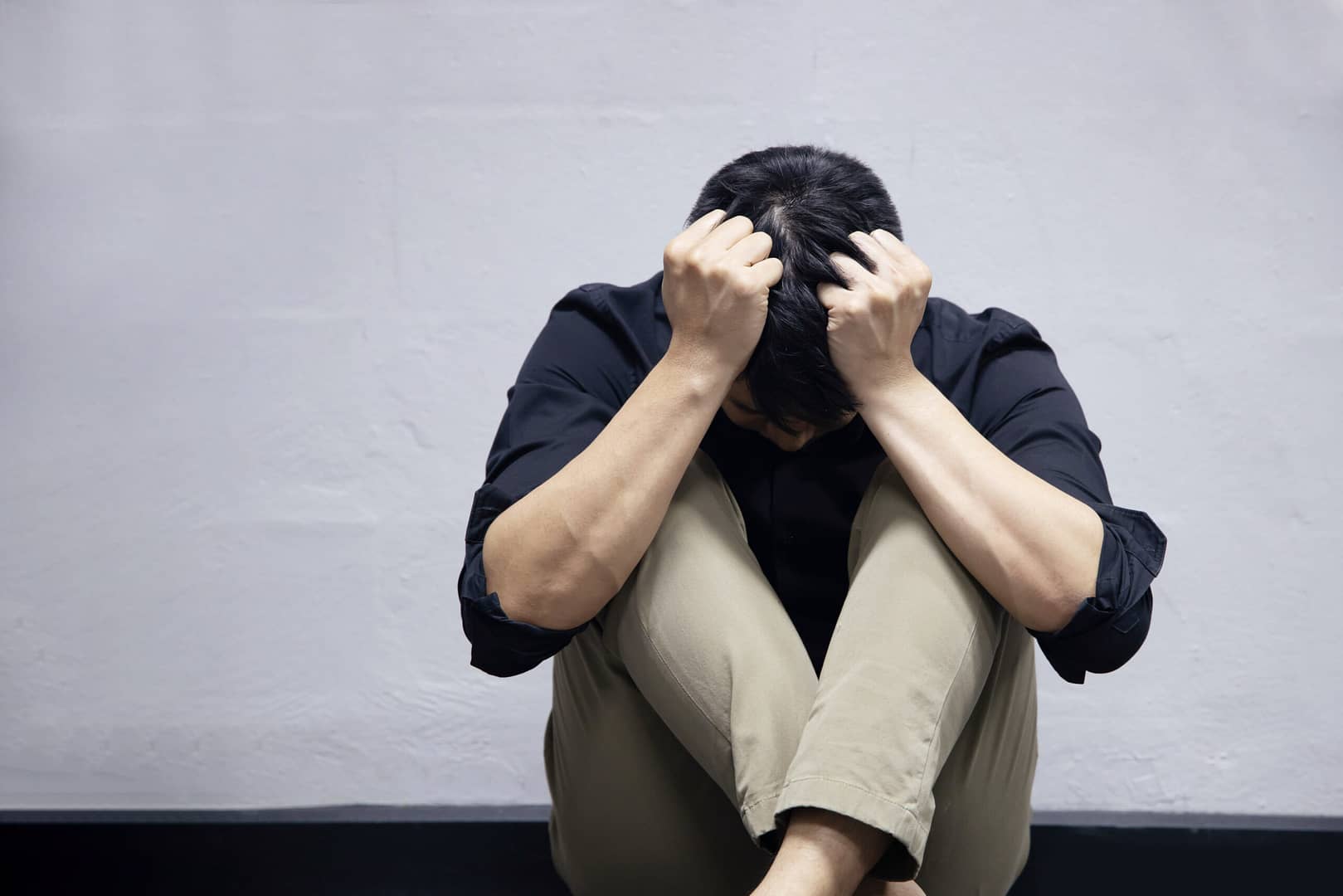 The Depression Businessman Sitting Near the Wall on the Floor